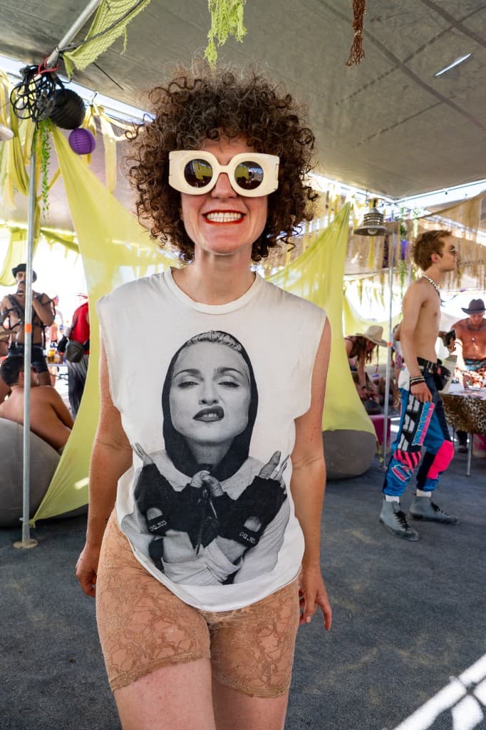 Camper in Madonna t-shirt and sunglasses at Mudskippers camp under the playa shade